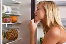 Задумчивая хозяйка, которая не знает, что ей выбрать в холодильнике.